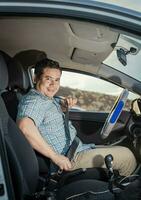 Happy driver putting on his seat belt, Smiling male driver putting on his seat belt. Concept of a driver in his car putting on his seat belt. Smiling person putting on seat belt photo