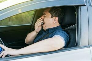 Tired driver yawning, concept of man yawning while driving. A sleepy driver at the wheel, a tired person while driving photo