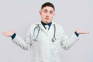 Puzzled doctor with open hands. Doubtful young doctor with open hands isolated. Insecure doctor concept isolated photo