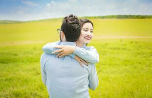 Close up of a happy couple hugging in the field, a young couple in love hugging in the green field, A man hugging his woman in a beautiful field photo
