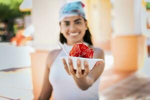 Close up of young woman holding a shaved ice in the street. Concept of a girl with a Nicaraguan raspado, Raspado of Nagarote. Smiling girl holding shaved ice on the street photo