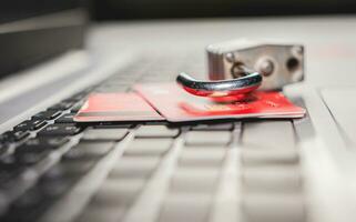 Credit card cyber security concept. Online vulnerability concept with credit card, Padlock on top of credit card on computer keyboard photo