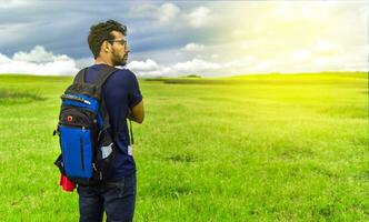 Adventurous man in the field, man with backpack in the field looking photo