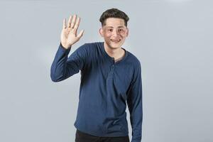 Man raising arm and waving friendly, isolated handsome man saying hi, friendly face man saying goodbye, concept of man saying hi on isolated background photo