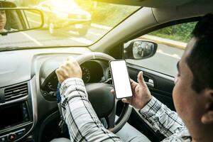 Distracted driver using the cell phone while driving, Man using his phone while driving, Person holding the cell phone and with the other hand the steering wheel, Concept of irresponsible driving photo
