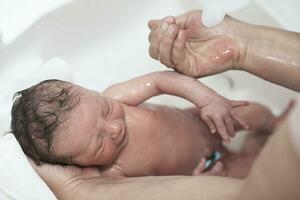 Newborn baby girl taking a first bath photo