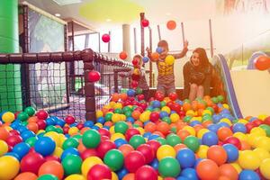 young mom playing with kids in pool with colorful balls photo