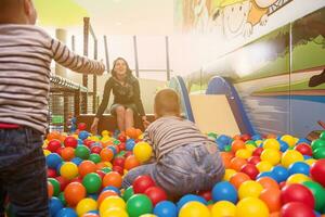 young mom playing with kids in pool with colorful balls photo