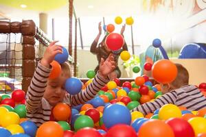 young mom playing with kids in pool with colorful balls photo