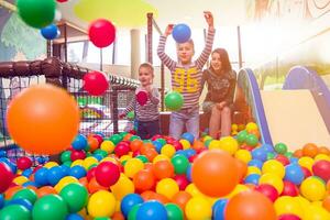 young mom playing with kids in pool with colorful balls photo