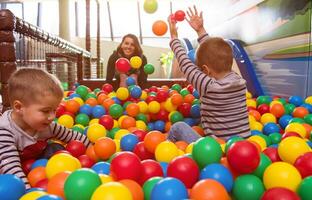 mamá joven jugando con niños en la piscina con bolas de colores foto