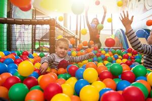 young mom playing with kids in pool with colorful balls photo