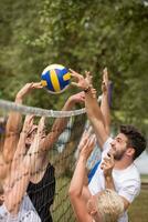 group of young friends playing Beach volleyball photo