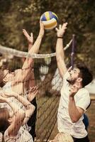 grupo de jóvenes amigos jugando voleibol de playa foto