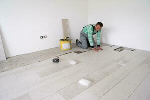 worker installing the ceramic wood effect tiles on the floor photo