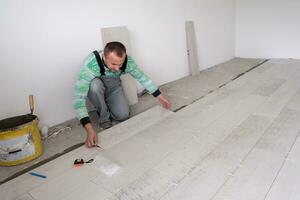 worker installing the ceramic wood effect tiles on the floor photo