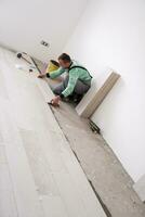 worker installing the ceramic wood effect tiles on the floor photo