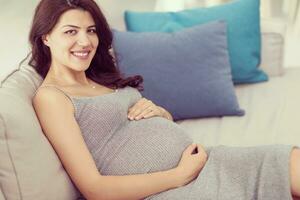 pregnant woman sitting on sofa at home photo