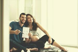 pareja embarazada revisando una lista de cosas para su bebé por nacer foto