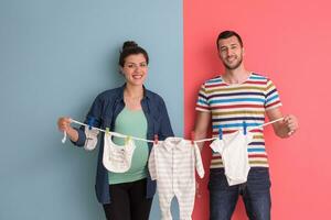 young couple holding baby bodysuits photo