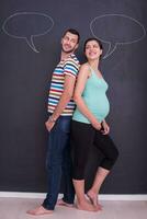 pregnant couple writing on a black chalkboard photo