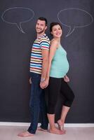 pregnant couple writing on a black chalkboard photo