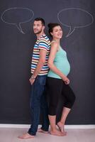 pregnant couple writing on a black chalkboard photo