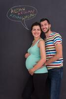 pregnant couple writing on a black chalkboard photo