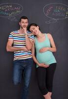 pregnant couple writing on a black chalkboard photo