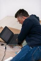 hombre usando una computadora portátil mientras está acostado en una caja de cartón foto