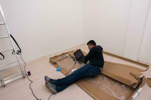 man using laptop while lying on cardboard box photo