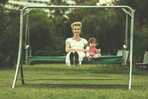 mother and little daughter swinging at backyard photo