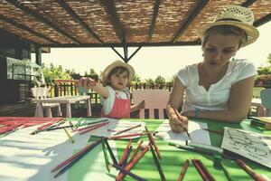 mamá y su pequeña hija dibujando imágenes coloridas foto