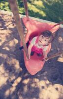 little girl swinging  on a playground photo