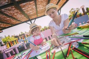 mamá y su pequeña hija dibujando imágenes coloridas foto