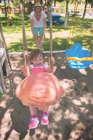 mother and daughter swinging in the park photo