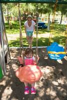 mother and daughter swinging in the park photo