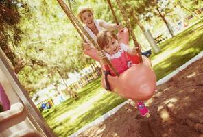 mother and daughter swinging in the park photo