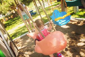 mother and daughter swinging in the park photo