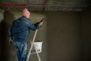 trabajador enyesando la pared con hormigón foto