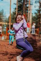 A little girl playing in the park. The concept of family socializing in the park. A girl swings on a swing, plays creative games photo