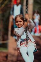 A little girl playing in the park. The concept of family socializing in the park. A girl swings on a swing, plays creative games photo