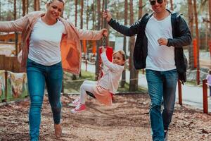 Family fun in the park. Happy family spending time in park and playing with their daughter photo