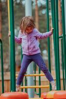 A little girl playing in the park. The concept of family socializing in the park. A girl swings on a swing, plays creative games photo