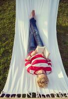woman reading a book while relaxing on hammock photo