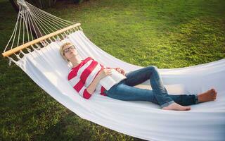 woman reading a book while relaxing on hammock photo