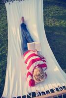 woman reading a book while relaxing on hammock photo