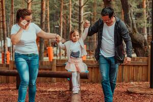 Family fun in the park. Happy family spending time in park and playing with their daughter photo