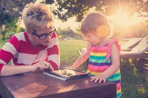 mom and her little daughter using tablet computer photo