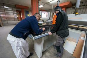 carpenters calculating and programming a cnc wood working machine photo